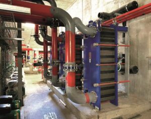 Alfa Laval plate heat exchanger installed in a mechanical plant room with red industrial pipework – supplied by AEL Heat Exchangers UK